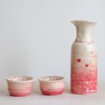 Two coil bowls and a coil vase with pink ombre glaze and small red hearts.