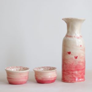 Two coil bowls and a coil vase with pink ombre glaze and small red hearts.