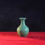 A small teal vase with a lip.