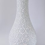 A tall, white vase with flower imprints.